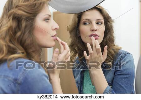 Picture - Woman examining her sore lips. Fotosearch