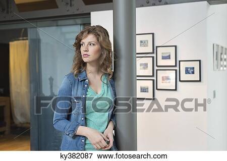Stock Photo - Woman leaning against a column and thinking. Fotosearch