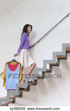 Stock Photography - Woman moving up stairs carrying clothes. Fotosearch