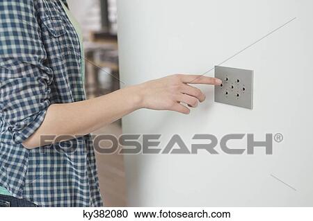 Woman pressing light switch on a wall View Large Photo Image Stock Image - Woman pressing light switch on a wall. Fotosearch