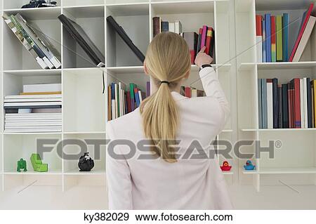 Woman taking out a book from shelf View Large Photo Image Stock Photo - Woman taking out a book from shelf. Fotosearch