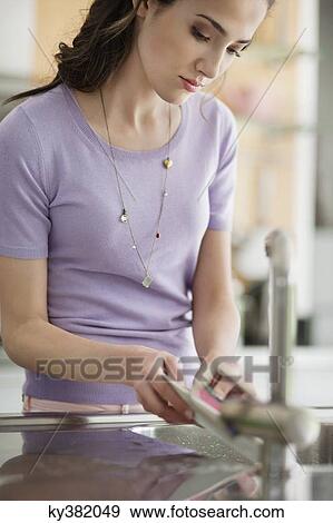 Woman washing dishes in the kitchen View Large Photo Image Stock Photo - Woman washing dishes in the kitchen. Fotosearch