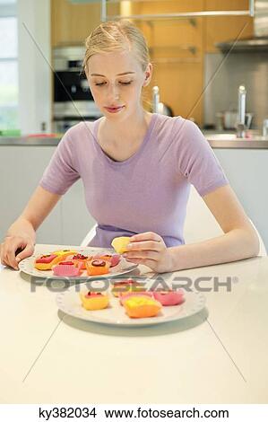 Picture - Woman with cakes at dining table. Fotosearch