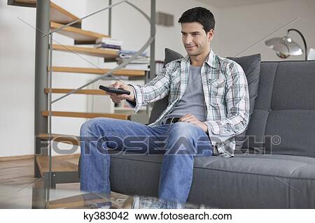 Stock Image - Man changing channels with a remote control. Fotosearch