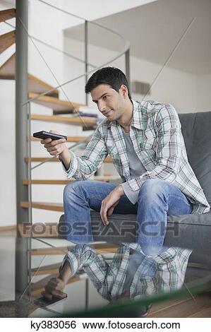 Man changing channels with a remote control View Large Photo Image Stock Photograph - Man changing channels with a remote control. Fotosearch