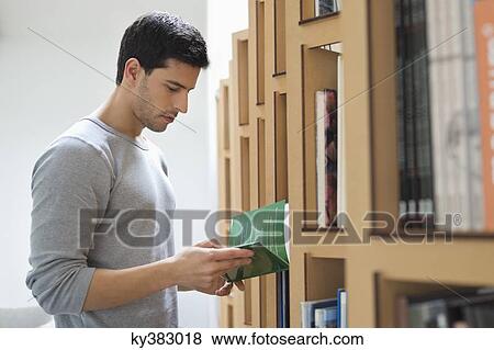 Man choosing a book from a bookshelf View Large Photo Image Stock Photo - Man choosing a book from a bookshelf. Fotosearch