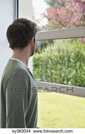 Picture - Man looking through a window. Fotosearch