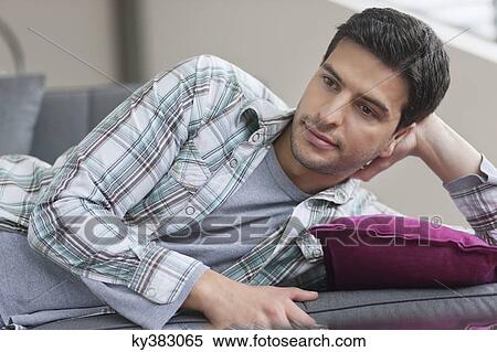 Stock Photography - Man lying on a couch and thinking. Fotosearch
