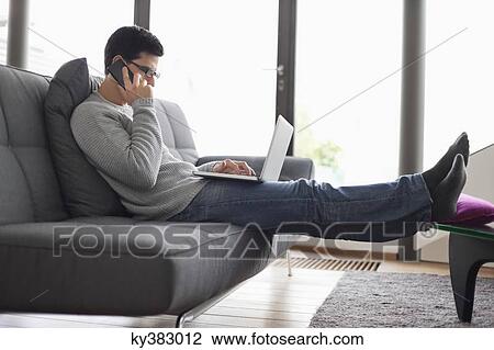 Man talking on a mobile phone while using a laptop View Large Photo Image Stock Image - Man talking on a mobile phone while using a laptop. Fotosearch