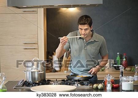 Man tasting food in the kitchen View Large Photo Image Stock Photo - Man tasting food in the kitchen. Fotosearch