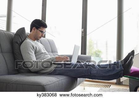 Man using a laptop on a couch View Large Photo Image Stock Photo - Man using a laptop on a couch. Fotosearch