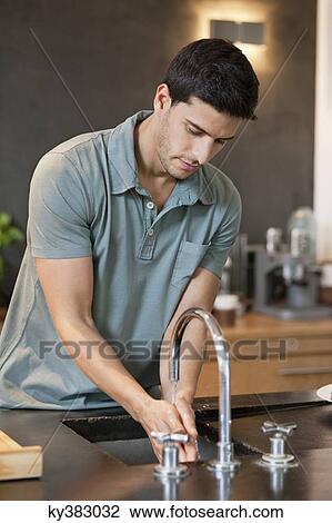 Man washing hands in the kitchen View Large Photo Image Stock Image - Man washing hands in the kitchen. Fotosearch