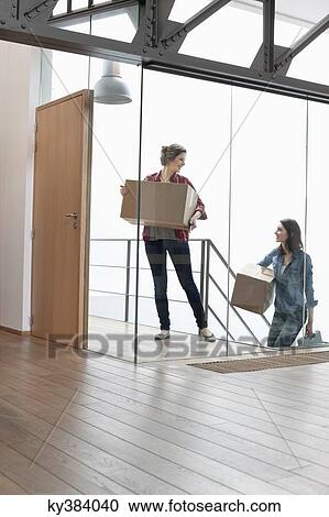 Two female friends carrying cardboard boxes at home View Large Photo Image Stock Image - Two female friends carrying cardboard boxes at home. Fotosearch