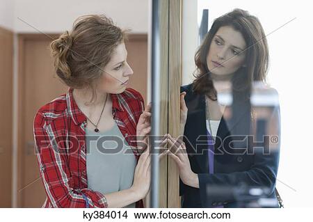 Two female friends standing back to back against a door View Large Photo Image Picture - Two female friends standing back to back against a door. Fotosearch
