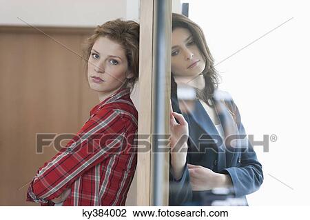 Two female friends standing back to back against a door View Large Photo Image Stock Image - Two female friends standing back to back against a door. Fotosearch