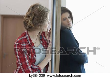 Stock Photo - Two female friends standing back to back against a door. Fotosearch