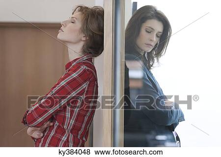 Two female friends standing back to back against a door View Large Photo Image Stock Photo - Two female friends standing back to back against a door. Fotosearch