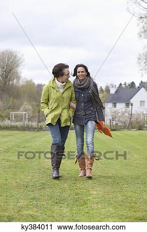 Two women walking in a lawn View Large Photo Image Stock Image - Two women walking in a lawn. Fotosearch