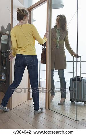 Stock Image - Woman welcoming her friend at doorway. Fotosearch