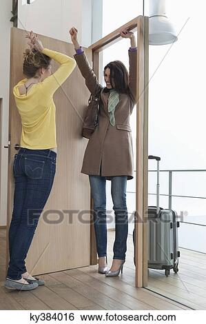 Woman welcoming her friend at doorway View Large Photo Image Stock Photograph - Woman welcoming her friend at doorway. Fotosearch