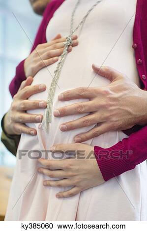 Close-up of a man's hand touching a pregnant woman's abdomen View Large Photo Image Stock Image - Close-up of a man's hand touching a pregnant woman's abdomen. Fotosearch