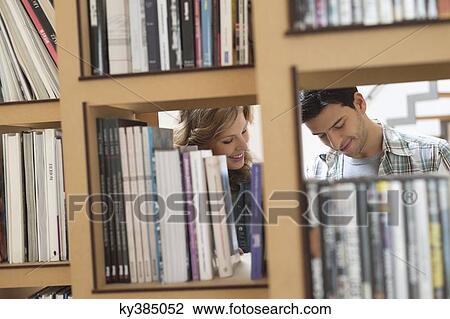 Couple choosing books from a bookshelf View Large Photo Image Stock Image - Couple choosing books from a bookshelf. Fotosearch