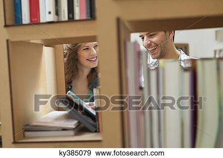 Couple choosing books from a bookshelf View Large Photo Image Stock Photo - Couple choosing books from a bookshelf. Fotosearch
