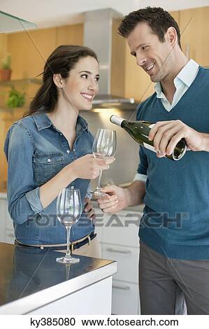 Stock Image - Couple drinking wine in the kitchen. Fotosearch