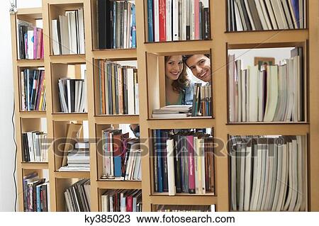 Couple peeking from a hole of a bookshelf View Large Photo Image Stock Image - Couple peeking from a hole of a bookshelf. Fotosearch