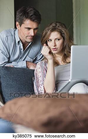 Couple using a laptop at home View Large Photo Image Stock Photography - Couple using a laptop at home. Fotosearch