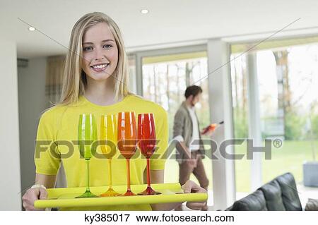 Stock Photo - Happy woman carrying glasses on a tray. Fotosearch