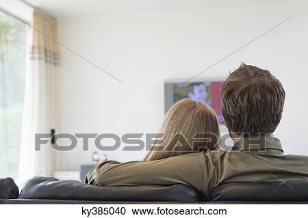 Rear view of a couple watching television View Large Photo Image Stock Image - Rear view of a couple watching television. Fotosearch
