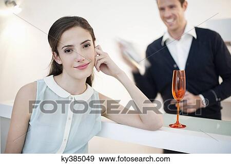 Woman smiling with her husband shaking cocktail in the background View Large Photo Image Stock Photo - Woman smiling with her husband shaking cocktail in the background. Fotosearch