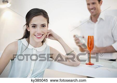 Woman smiling with her husband shaking cocktail in the background View Large Photo Image Stock Photography - Woman smiling with her husband shaking cocktail in the background. Fotosearch