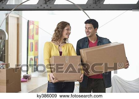 Couple carrying cardboard boxes and smiling View Large Photo Image Stock Photo - Couple carrying cardboard boxes and smiling. Fotosearch