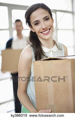 Stock Photo - Couple carrying cardboard boxes at their new home. Fotosearch