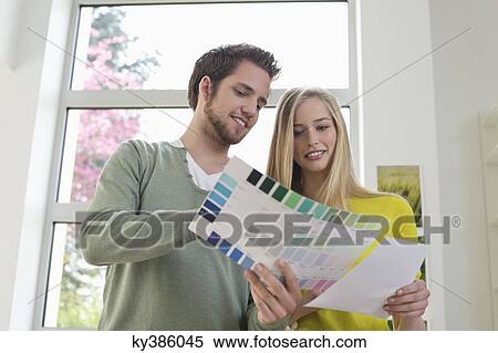 Stock Photography - Couple choosing color for their house from a color chart. Fotosearch