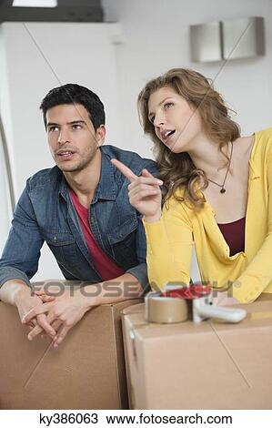 Couple leaning over cardboard boxes discussing View Large Photo Image Stock Image - Couple leaning over cardboard boxes discussing. Fotosearch