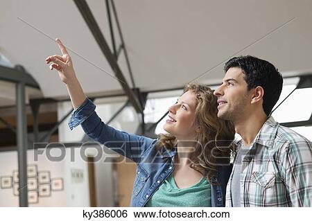 Happy woman pointing with her husband beside her View Large Photo Image Stock Photograph - Happy woman pointing with her husband beside her. Fotosearch