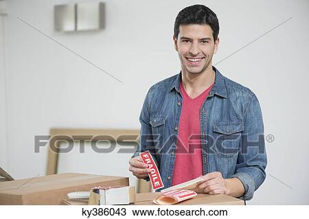 Man sticking 'Fragile' sticker on cardboard boxes View Large Photo Image Stock Image - Man sticking 'Fragile' sticker on cardboard boxes. Fotosearch