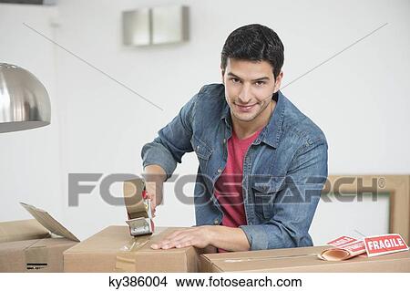 Picture - Man taping up a cardboard box. Fotosearch