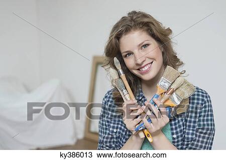 Portrait of a woman holding paintbrushes and smiling View Large Photo Image Stock Image - Portrait of a woman holding paintbrushes and smiling. Fotosearch
