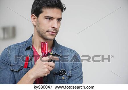 Technician holding screwdrivers and thinking View Large Photo Image Stock Photo - Technician holding screwdrivers and thinking. Fotosearch