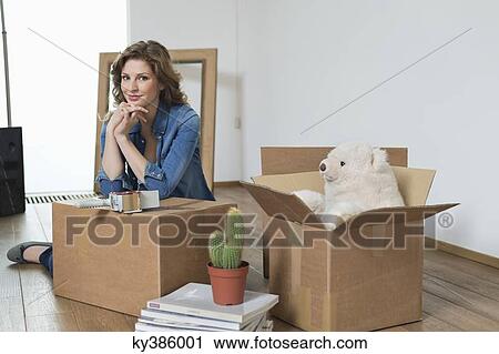 Woman leaning on a cardboard box and smiling View Large Photo Image Stock Image - Woman leaning on a cardboard box and smiling. Fotosearch