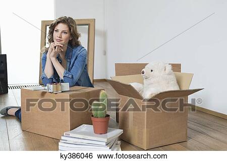 Woman leaning on cardboard box and thinking View Large Photo Image Stock Photograph - Woman leaning on cardboard box and thinking. Fotosearch