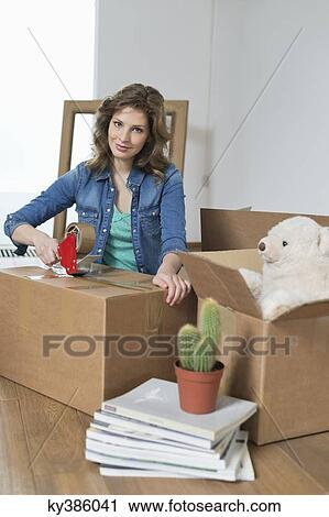 Woman taping up cardboard box View Large Photo Image Stock Image - Woman taping up cardboard box. Fotosearch