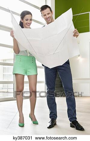 Stock Image - Couple reading a blueprint at their new home. Fotosearch