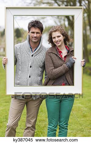 Portrait of a couple holding a frame View Large Photo Image Stock Photography - Portrait of a couple holding a frame. Fotosearch