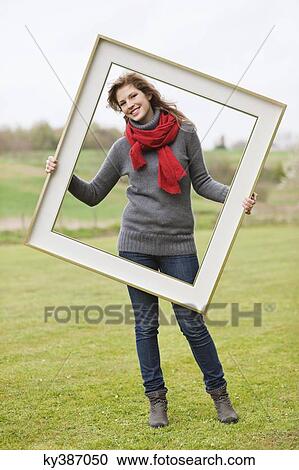 Portrait of a woman standing with a frame in a park View Large Photo Image Stock Image - Portrait of a woman standing with a frame in a park. Fotosearch