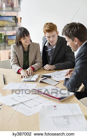 Stock Image - Real estate agent discussing property documents to his clients. Fotosearch
